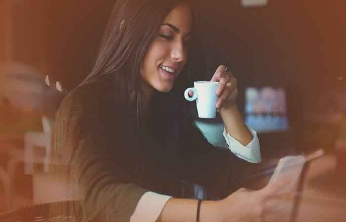 Девушка с телефоном пьёт кофе