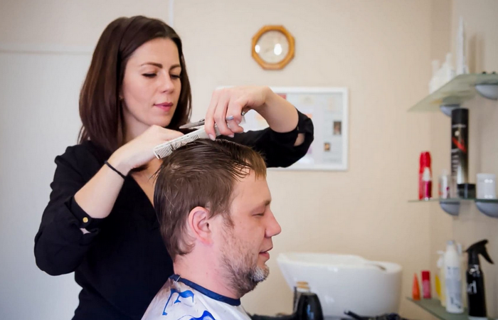 Девушка парикмахер стрижет мужчину
